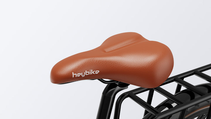 Brown leather HeyBike- Cityrun ebike seat with the logo "heybike" on a metal bike rack, set against a plain gray background.