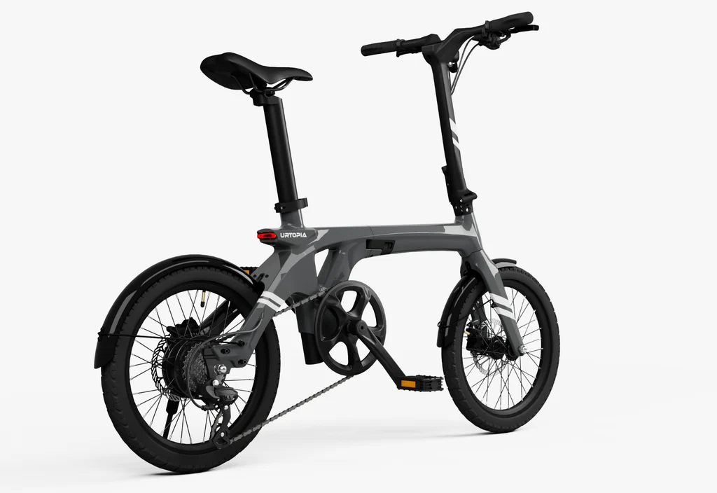 The Urtopia - Carbon Fold 1 is a gray folding all-terrain eBike by Urtopia, featuring a sleek carbon fiber frame with black wheels, pedals, and handlebars, displayed on a plain white background.
