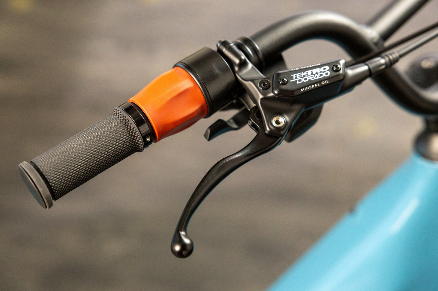 Close-up of a bicycle handlebar featuring a black grip and a brake lever with "Momentum - Cito E+, mineral oil" label, from Tampa Bay eBikes.