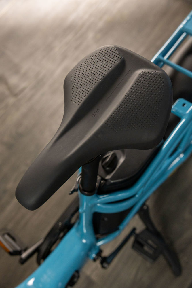 Close-up of a black bicycle seat on a turquoise Momentum Cito E+ bike frame, highlighting the seat's texture and contour.