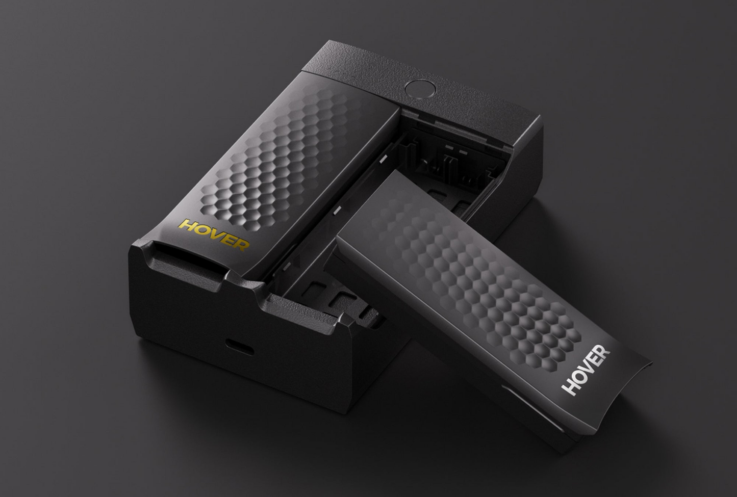 A sleek black HOVERAir Charging Hub with a honeycomb pattern and "HOVER" in bold yellow and white features a sliding component, partially extended on a dark surface, and is known for its fast charging capabilities.