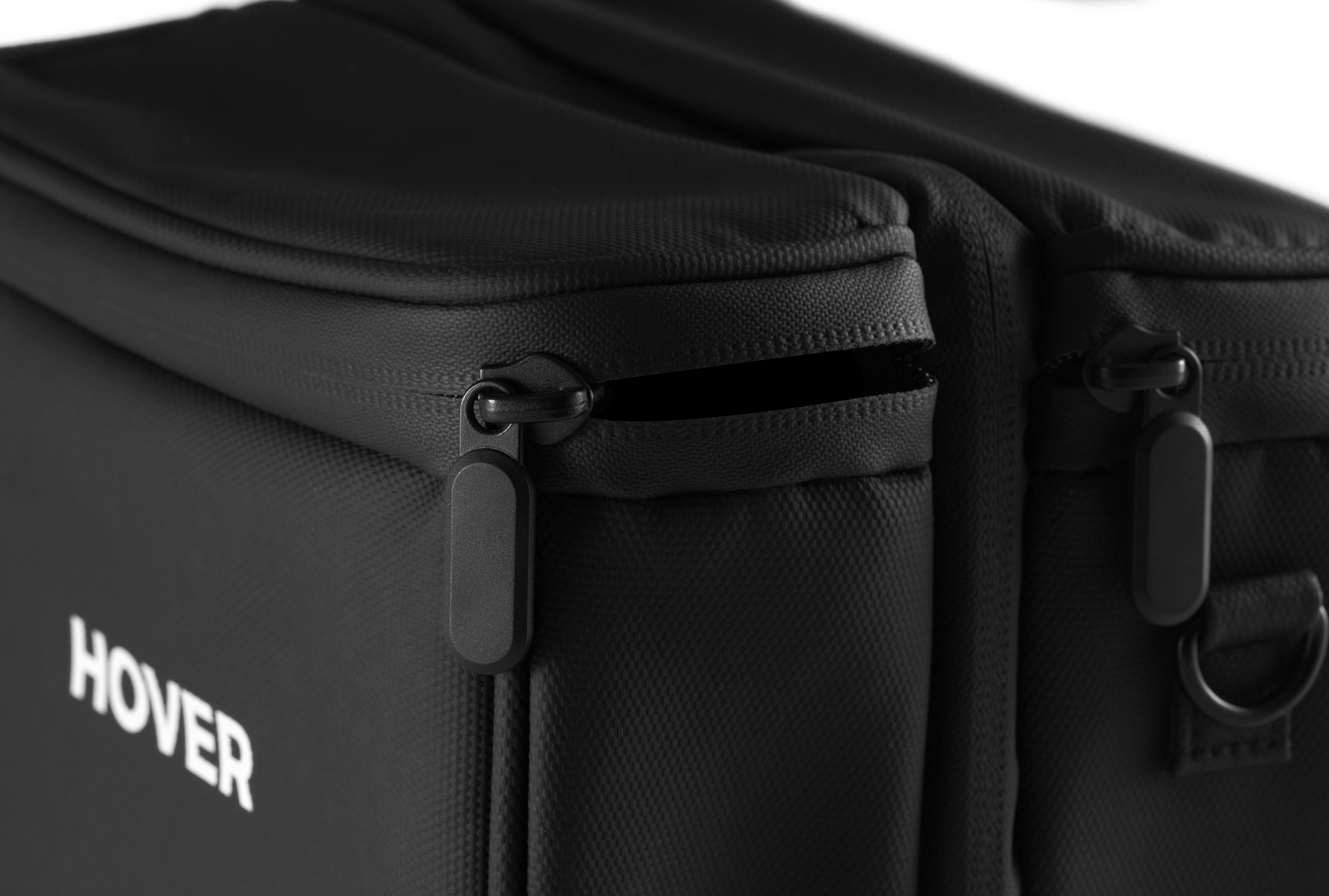 Close-up of a black zipper on a textured black fabric bag with "HOVERAir" text visible, designed to perfectly fit your HOVERAir Carry Bag.