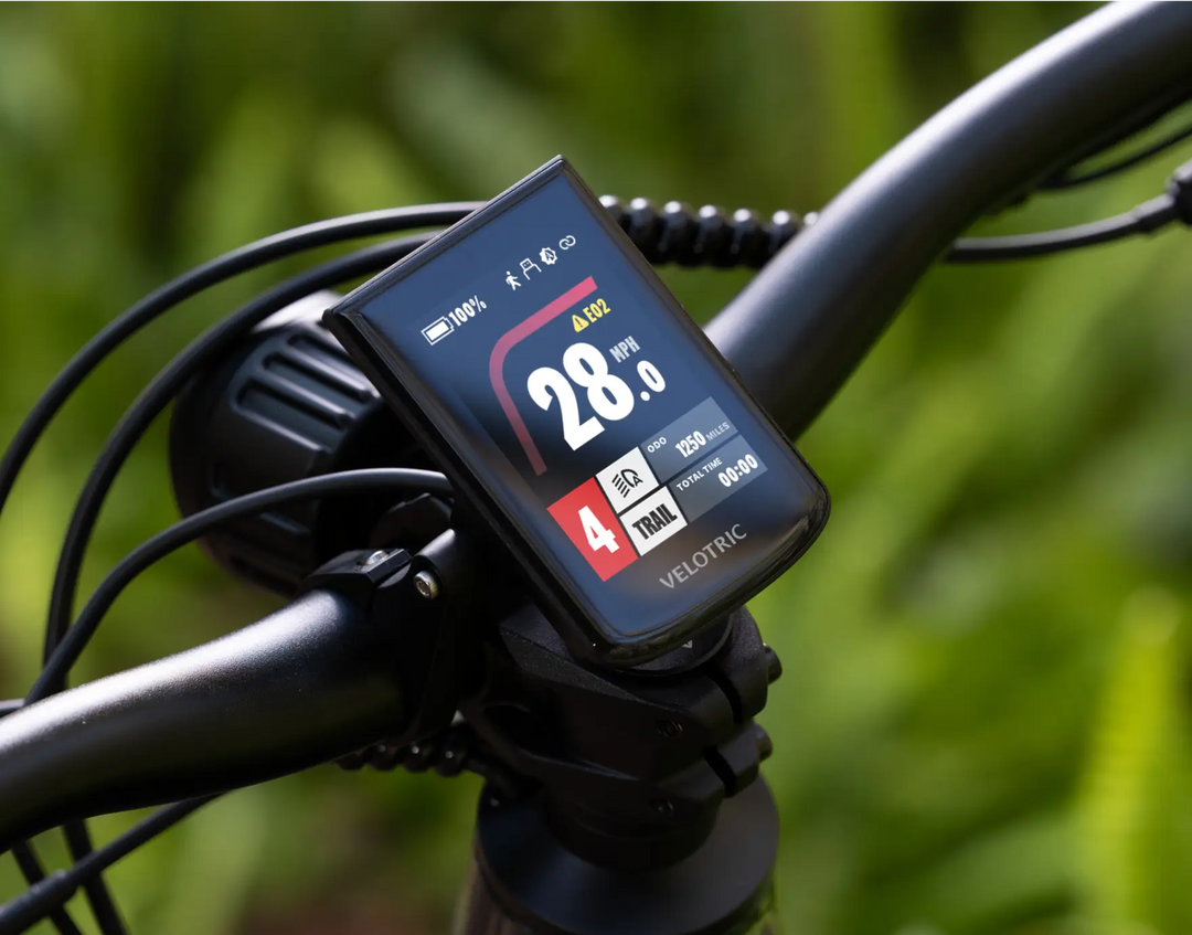 Velotric eBike handlebar with a Velotric Summit 1 digital cycling computer displaying speed, gear, and battery level.