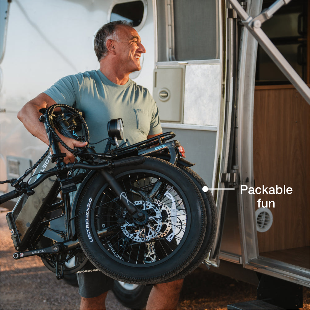 A man carrying a Lectric - XP4 folding eBike enters an RV, with a label on the bike that reads "Packable fun.