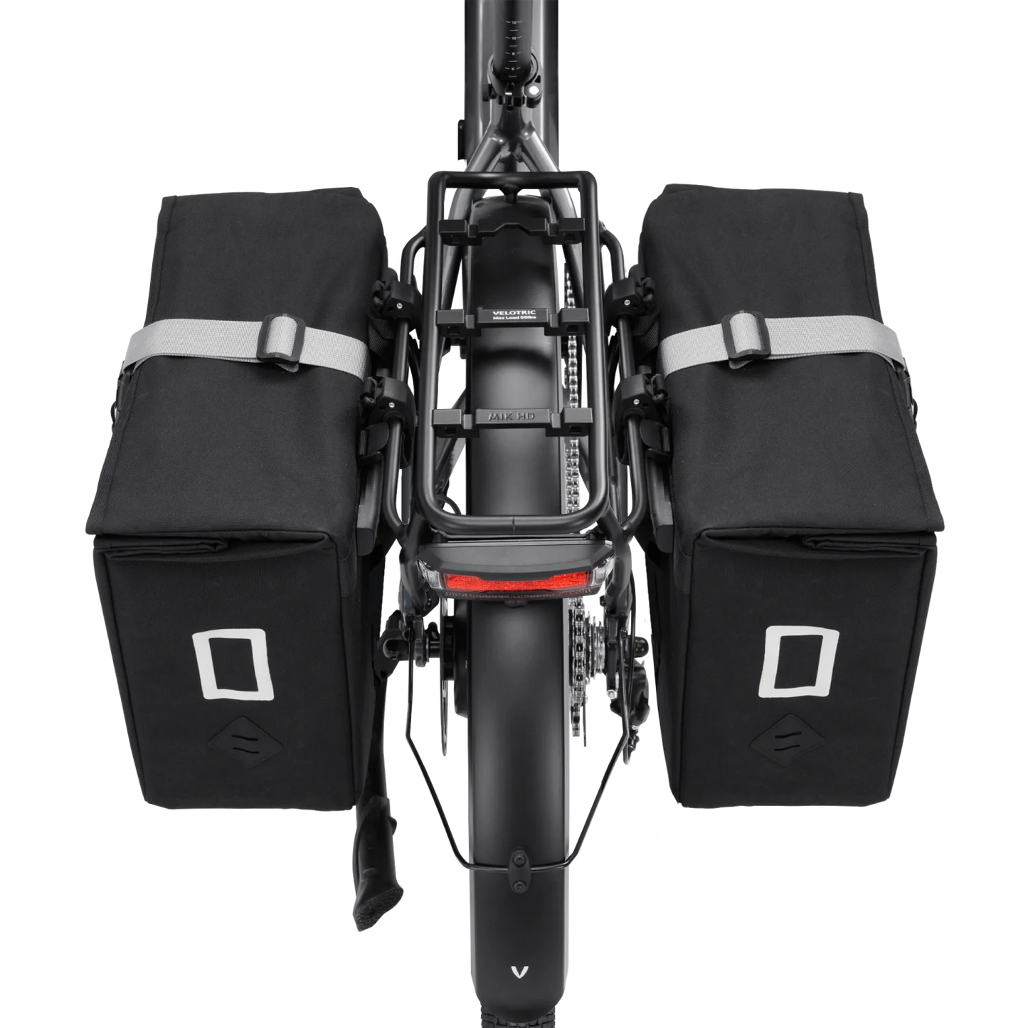 Rear view of an eBike with two Velotric - Rear Rack Pannier Bags by Velotric, mounted on either side of the rear wheel and rack. They feature reflective accents and a waterproof utility design.
