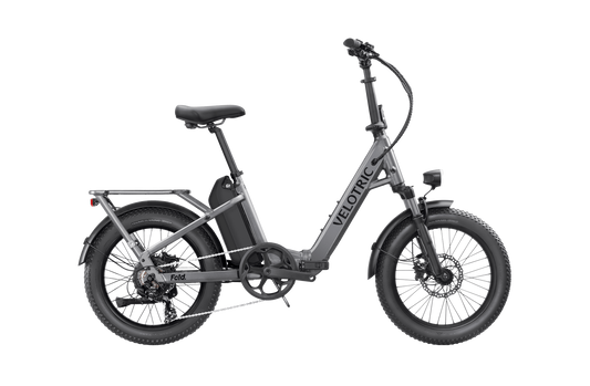 Folded Velotric - Fold 1 with visible branding, featuring a step-through frame and rear wheel mudguard, isolated on a black background.