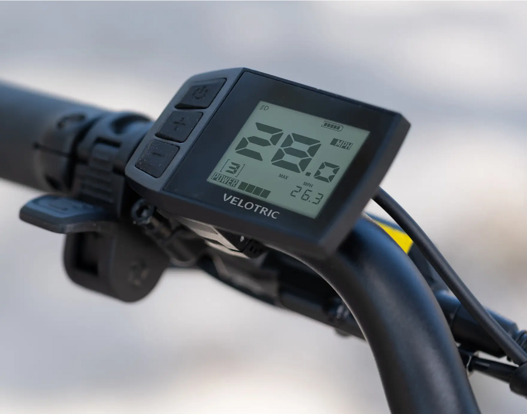 Close-up of a Velotric Fold 1 eBike's digital display showing speed and battery status on the handlebar.