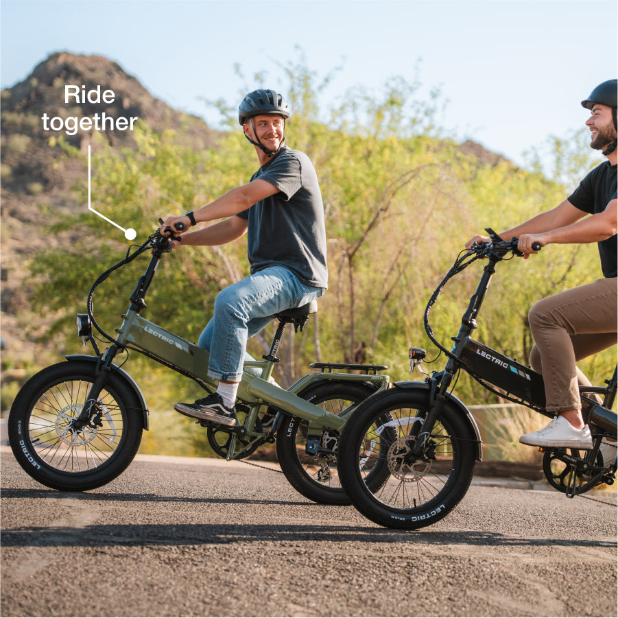 Two riders wearing helmets cruise on Lectric XP4 folding eBikes along an outdoor trail lined with trees and mountains. Text reads, "Ride together.