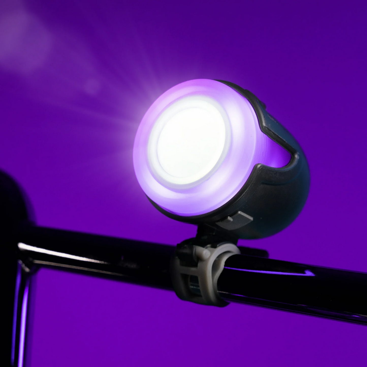 The Brightz Halo Brightz is a sleek, weather-resistant bicycle headlight that mounts to handlebars, emitting a brilliant white light with a purple glow—perfect for night rides against vibrant backgrounds.