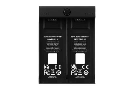 Two black HOVERAir batteries labeled "ZERO ZERO ROBOTICS" sit in a HOVERAir Charging Hub, showcasing regulatory markings and company information. These batteries are designed to prioritize safety features for optimal performance.