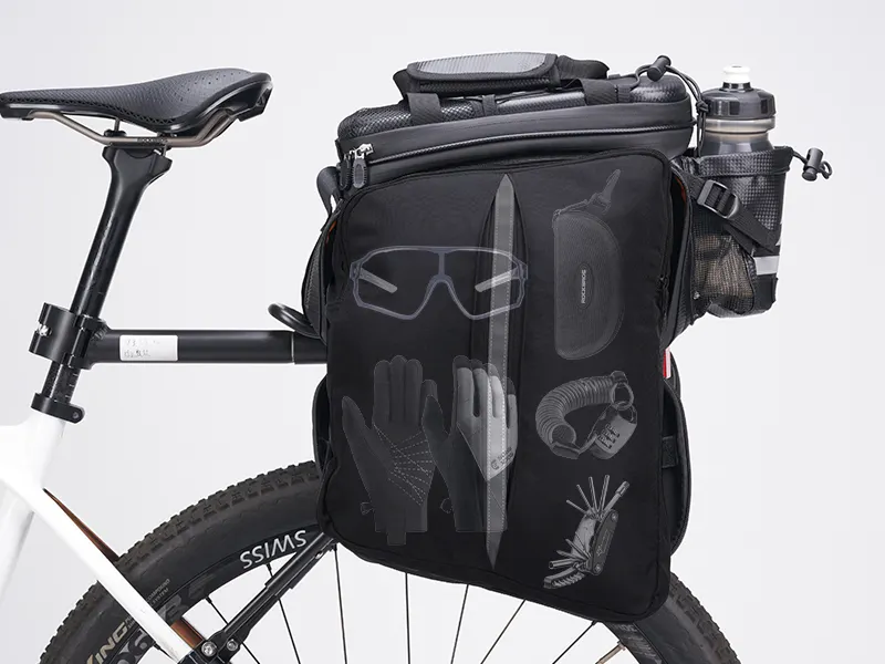 Close-up of a bicycle featuring Tampa Bay eBikes' Rear Rack Bag with Panniers, displaying cycling gear like gloves, goggles, helmet, pump, patch kit, and a water bottle in a frame holder.