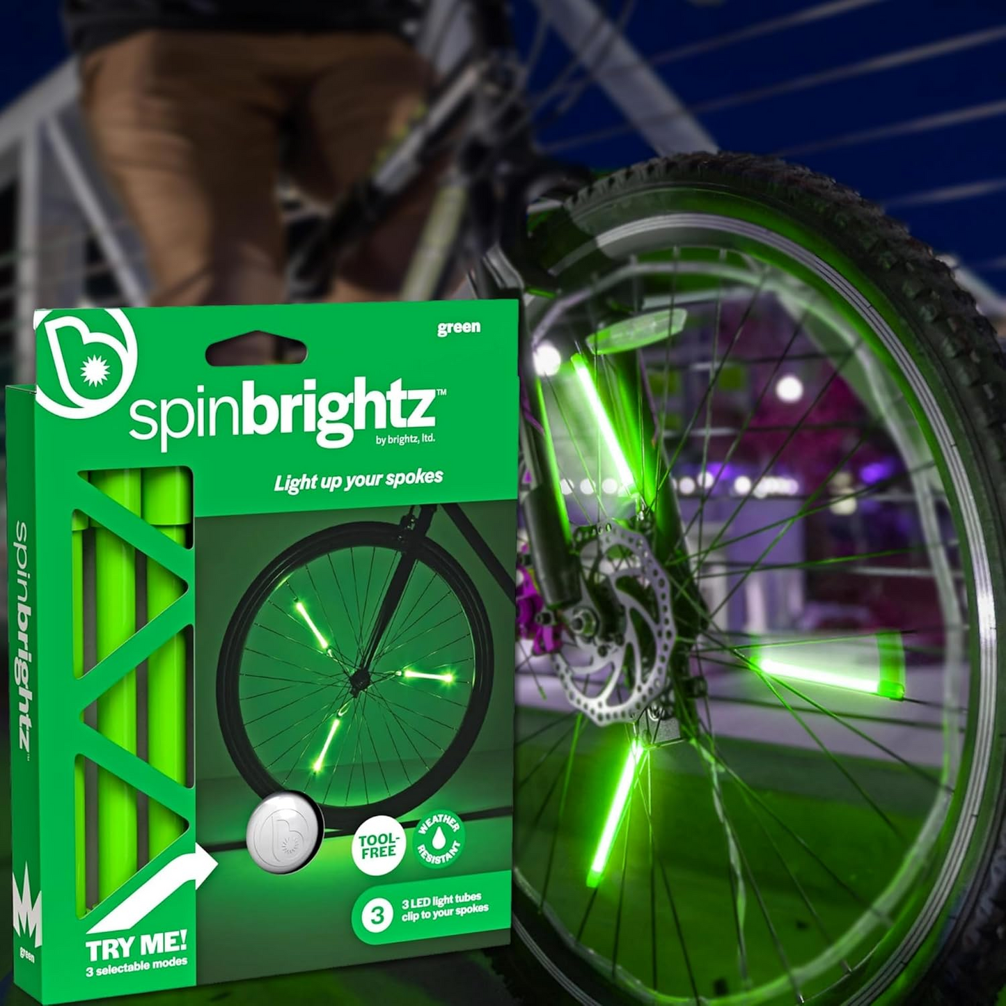 Bicycle with green LED light-up spokes and a weather-resistant design, next to a box labeled "Spin Brightz" from the Brightz brand.