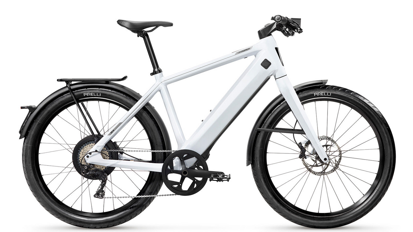 White modern electric bicycle Stromer - ST3 Sport with a sleek frame, equipped with Pirelli tires, disc brakes, a Gates carbon belt, and a rear carrier, isolated on a white background.