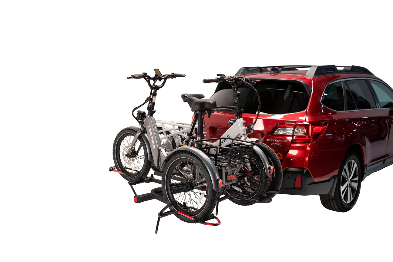 A red SUV with two Hollywood Racks - Trike Adapter Kits For Sport Rider attached to it using a hitch.