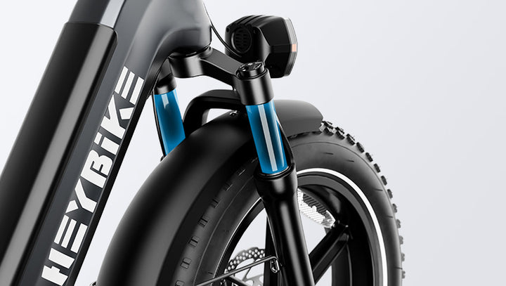 Close-up of a HeyBike- Ranger S's front suspension system and tire, featuring bold branding on the frame.