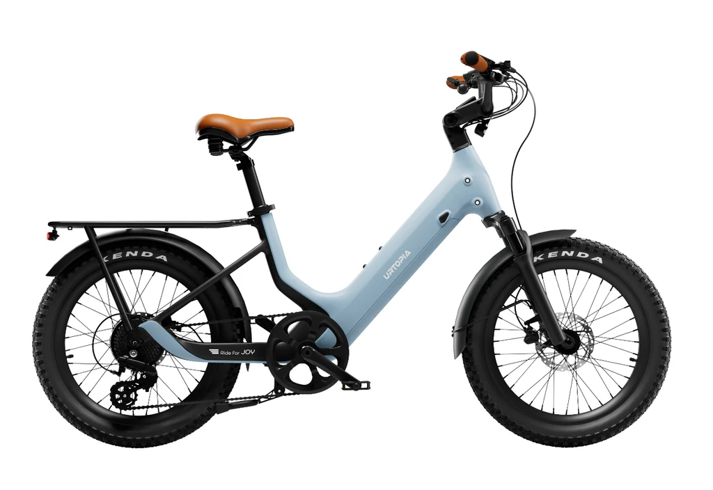The Urtopia - Joy Carbon by Urtopia is a light blue electric bicycle with a step-thru frame, wide tires, brown saddle, rear cargo rack, and front and rear disc brakes, displayed on a white background.