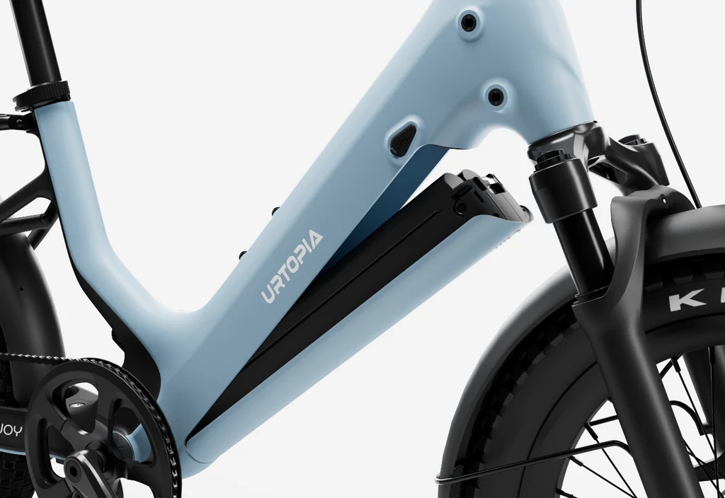 Close-up of the Urtopia - Joy Carbon eBike’s light blue carbon frame, showcasing the removable Samsung Li-ion battery compartment, front suspension fork, and crankset.