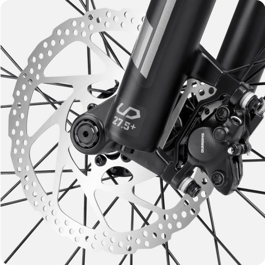 Close-up of a Velotric - Summit 1 eBike disc brake and front wheel suspension fork, showcasing a detailed view of the brake mechanism and wheel spokes.