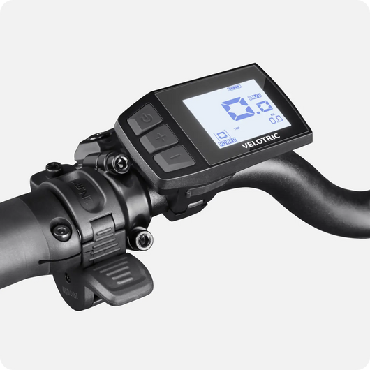 Digital bicycle computer mounted on a Velotric Fold 1 eBike handlebar, displaying speed and battery status on its screen, isolated on a white background.