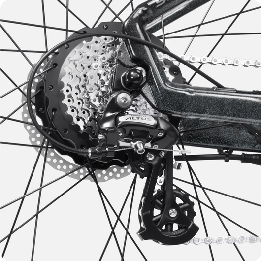 Close-up of a bicycle's rear wheel, showcasing the derailleur, chain, and cogset of the Velotric Summit 1 eBike, with intricate black spokes on a white background.