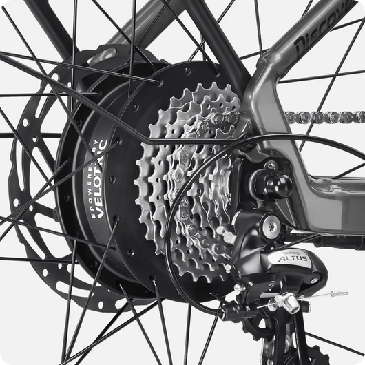 Close-up of a bicycle's rear wheel showing the gear cassette, disc brake rotor, and Shimano Altus derailleur, showcasing Velotric - Discover 2's advanced eBike engineering by Velotric.