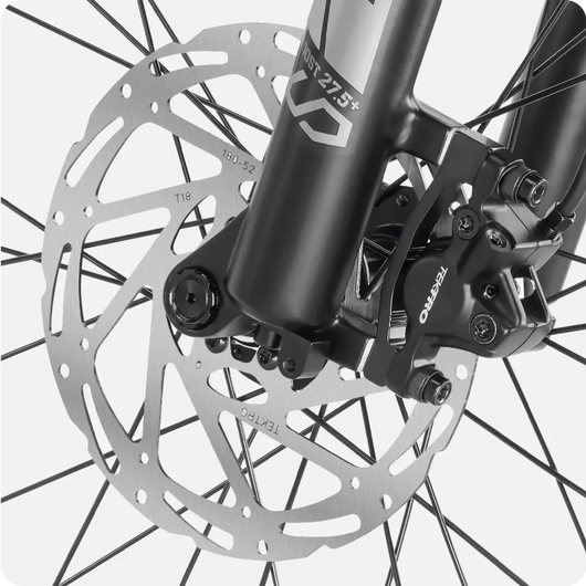 Close-up of a Velotric - Discover 1's front disc brake system, featuring a Tektro caliper and a large silver rotor mounted on the electric bike's fork.