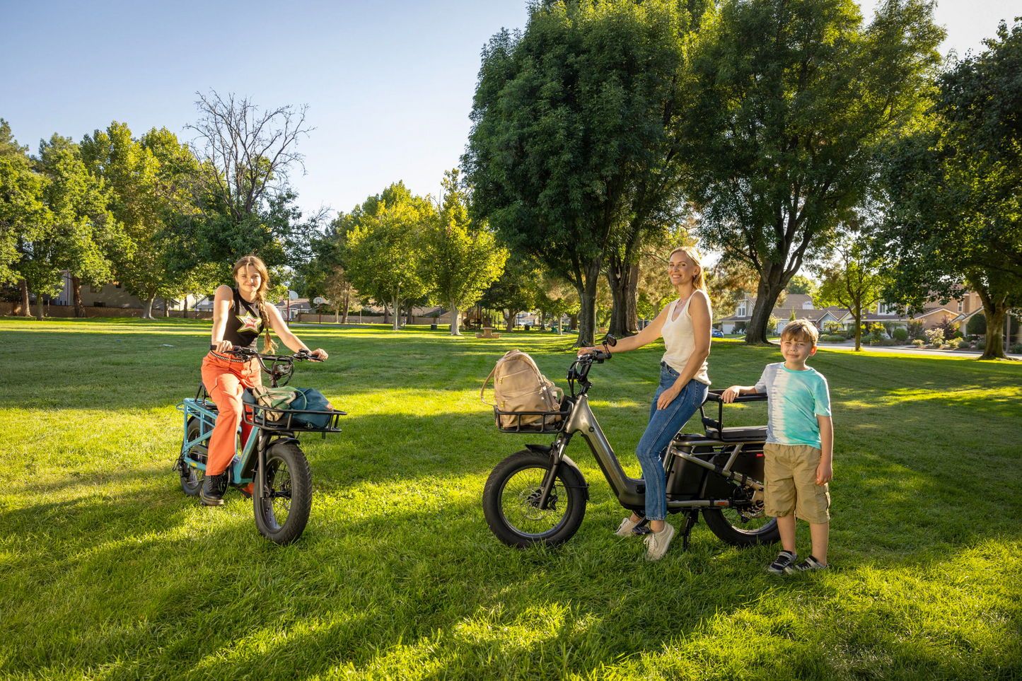 Family with two adults and a child standing next to Momentum - Cito E+ in a sunny park, smiling at the camera.