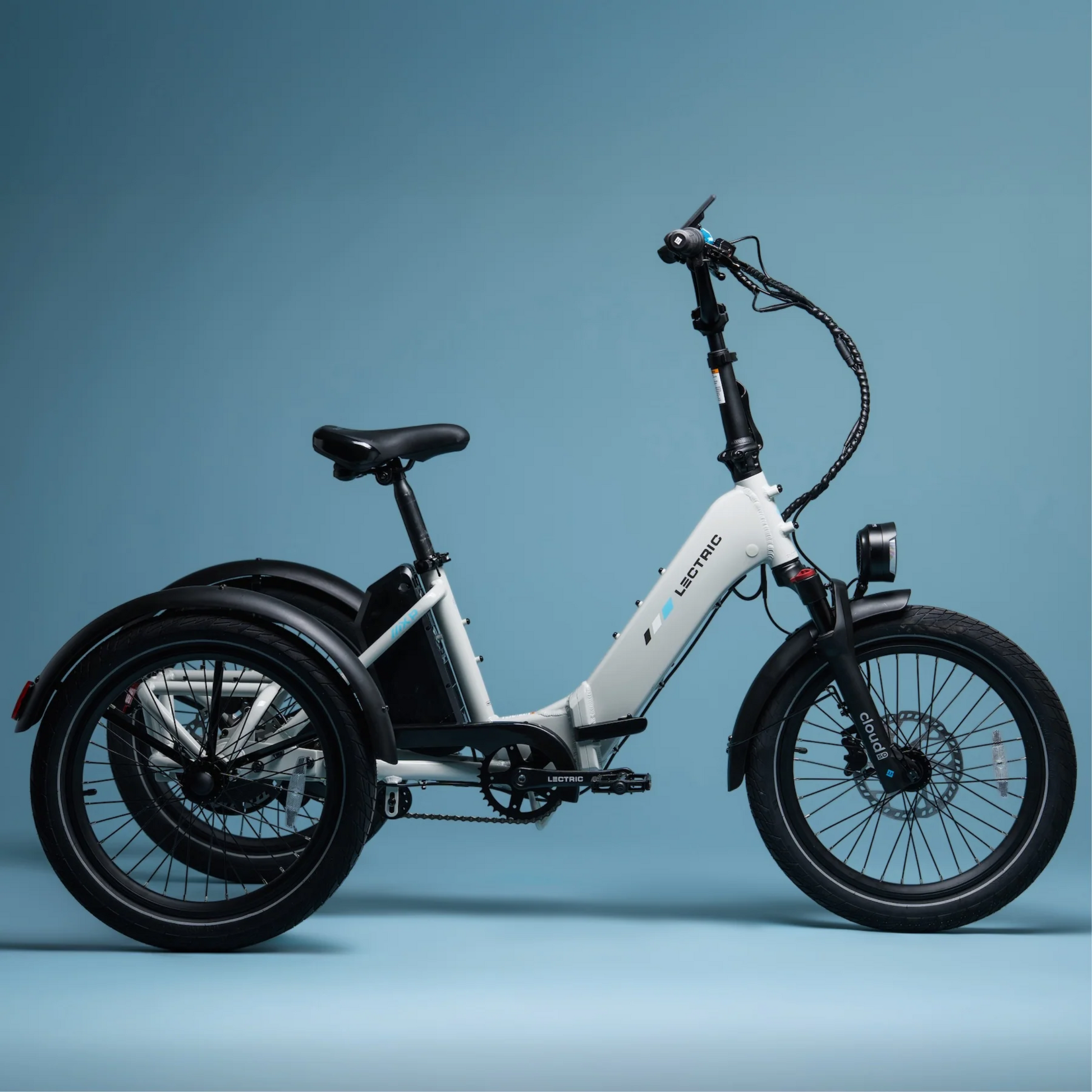 The Lectric - XP Trike2 by Lectric is a white electric tricycle with a step-through frame, long range, black handlebars, and two rear wheels, shown against a plain blue background.