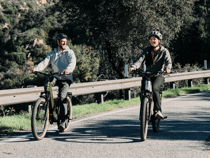 Two helmeted riders on Velotric Discover M electric bikes in manufacturer lifestyle photography