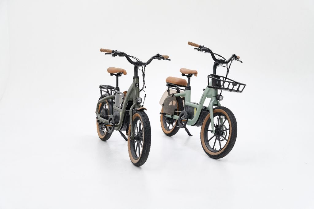 Two Segway Muxi electric bikes with fat tires, brown saddles, and black handlebars are displayed on a white background. One family bike from Segway includes a front basket, while the other does not.