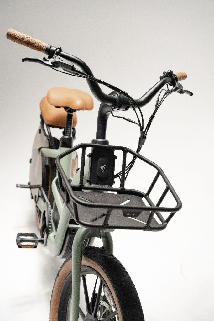 Front view of a green Segway Muxi electric utility bike by Segway featuring a black wire basket, brown seat, and brown handlebar grips, shown against a plain white background.