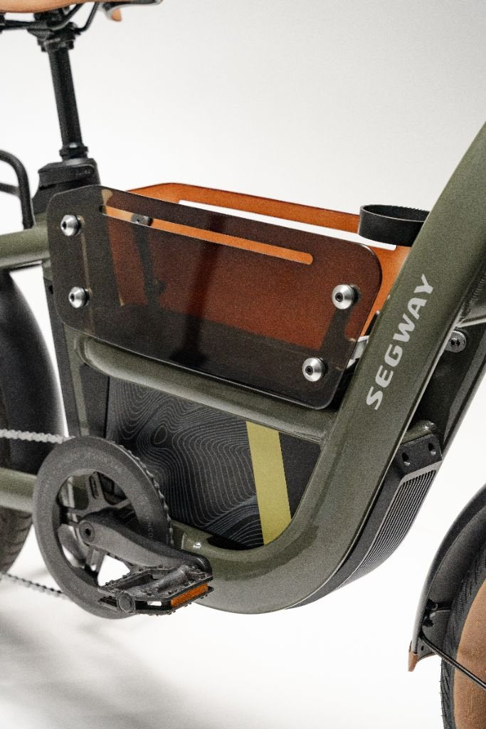 Close-up of the Segway Muxi by Segway, highlighting its pedal, frame section, a storage compartment with a translucent panel, and chain mechanism.