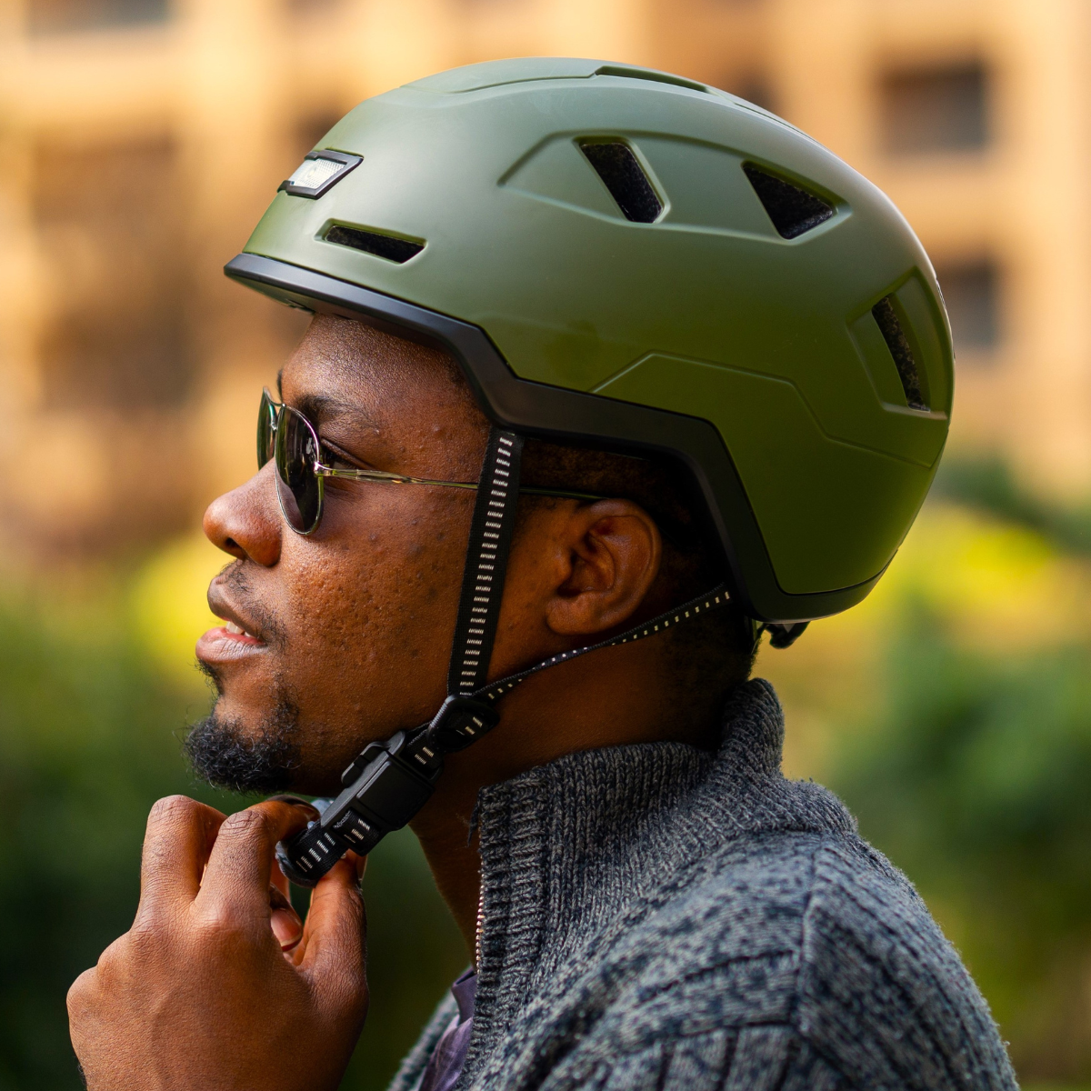 Man securing the strap of his XNITO CPSC certified Moss green helmet.