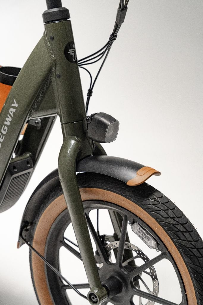 Close-up of the Segway Muxi's front wheel, highlighting the tire, fender, headlight, and brake cables by Segway against a plain background.