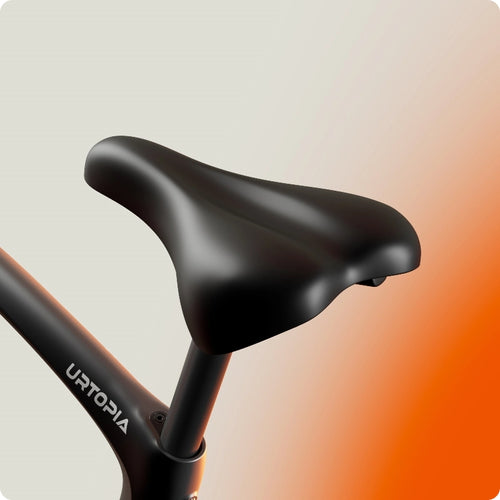 Close-up of a black seat on the Urtopia - Carbon Classic eBike frame, highlighting its sleek design by Urtopia against a gradient beige-to-orange background.