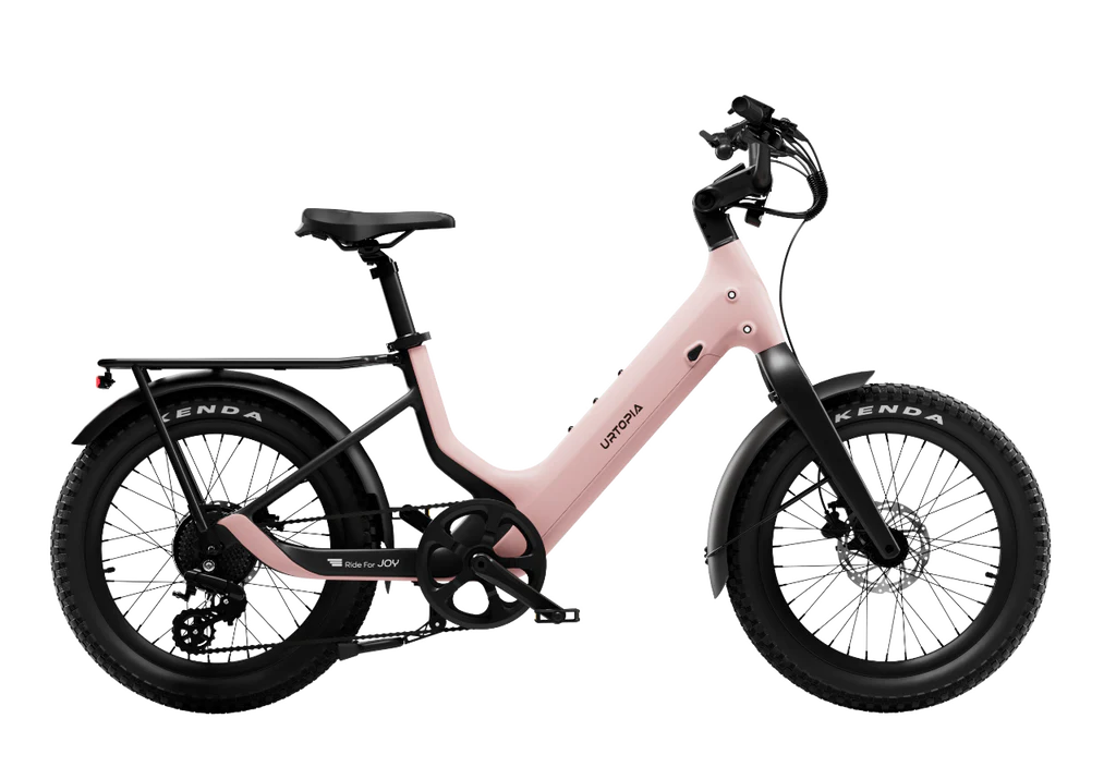 The Urtopia Carbon Joy Ultra by Urtopia is a pink electric cruiser with thick tires, disc brakes, front and rear fenders, a rear rack, and a long-range battery, shown on a white background.