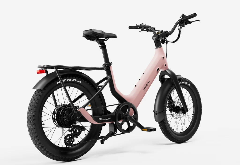 The Urtopia Carbon Joy Ultra by Urtopia is a pink and black long-range electric bike with thick tires, a rear cargo rack, and a step-through frame, shown from a rear-side angle on a white background.