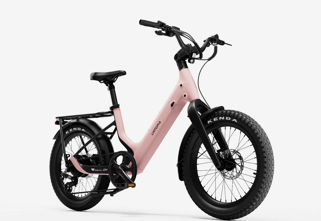 The Urtopia Carbon Joy Ultra by Urtopia, a pink electric cruiser bike with a step-through frame, wide tires, rear cargo rack, and front and rear fenders, is displayed against a white background.
