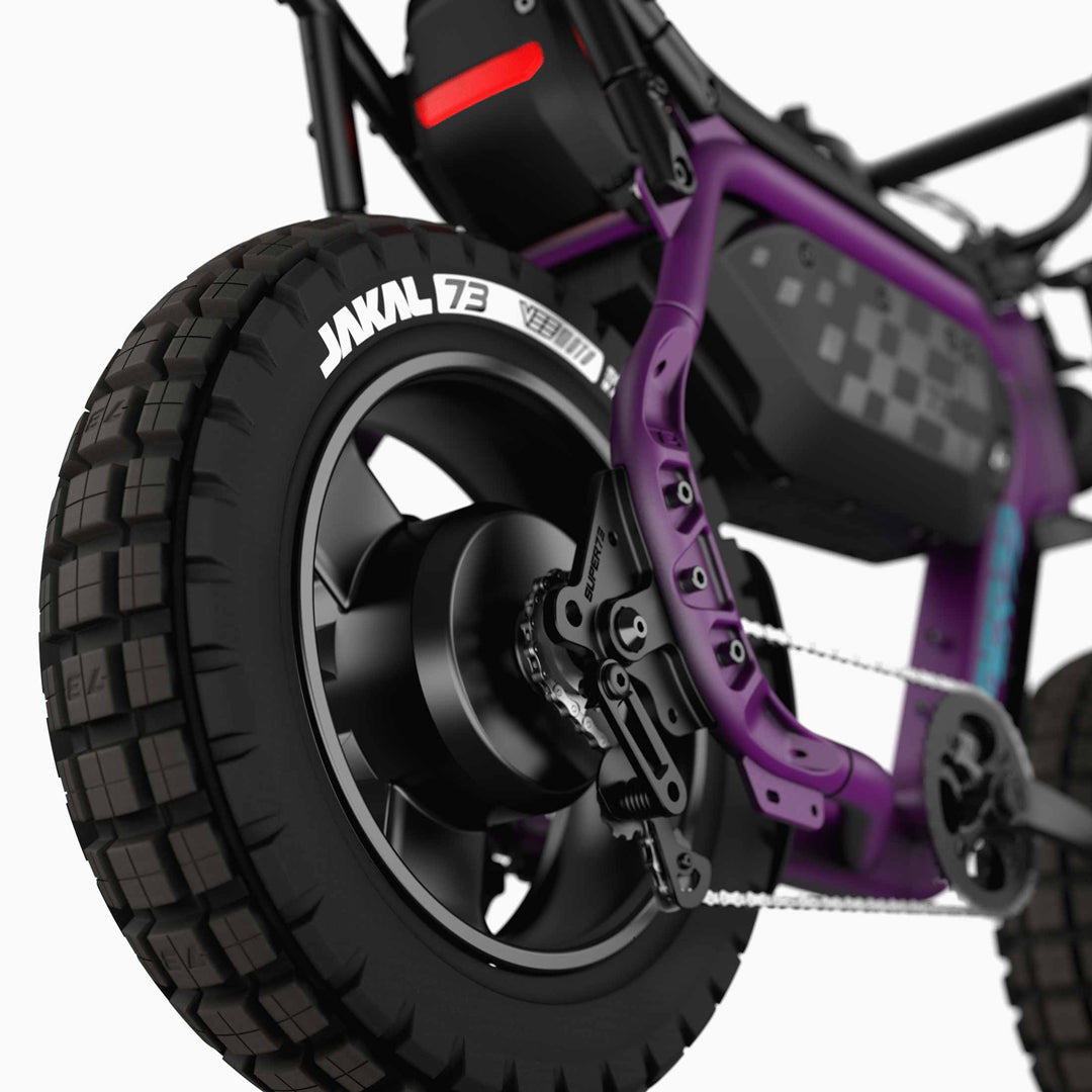 Close-up of the rear wheel and chain mechanism on a purple Super 73 - MZFT electric bike by Super 73, highlighting rugged tires and a visible battery pack.