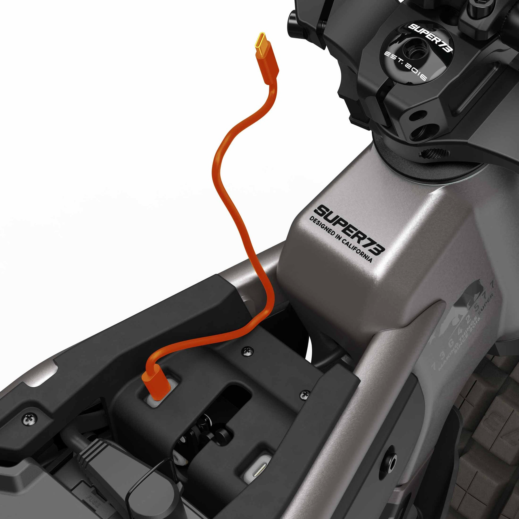 Close-up of a Super 73 - MZFT eBike frame with an orange charging cable plugged in near the seat and "Super 73" branding visible, emphasizing this iconic urban electric bike.
