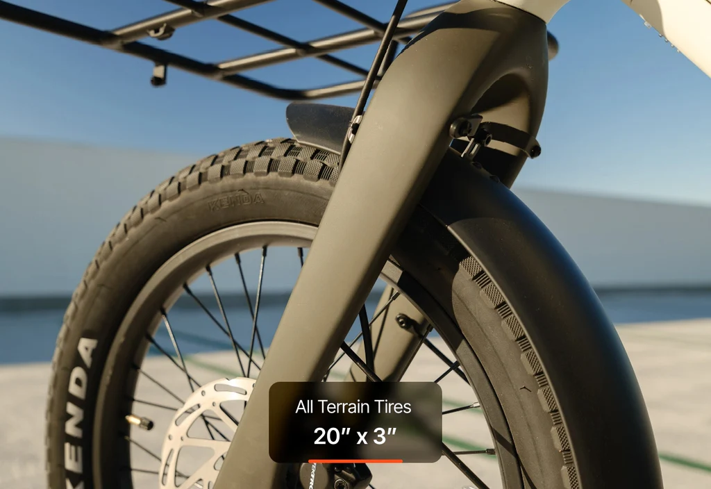 Close-up of the Urtopia - Carbon Joy Ultra e-bike's 20" x 3" all-terrain front tire, disc brake, and part of the front cargo rack by Urtopia visible.