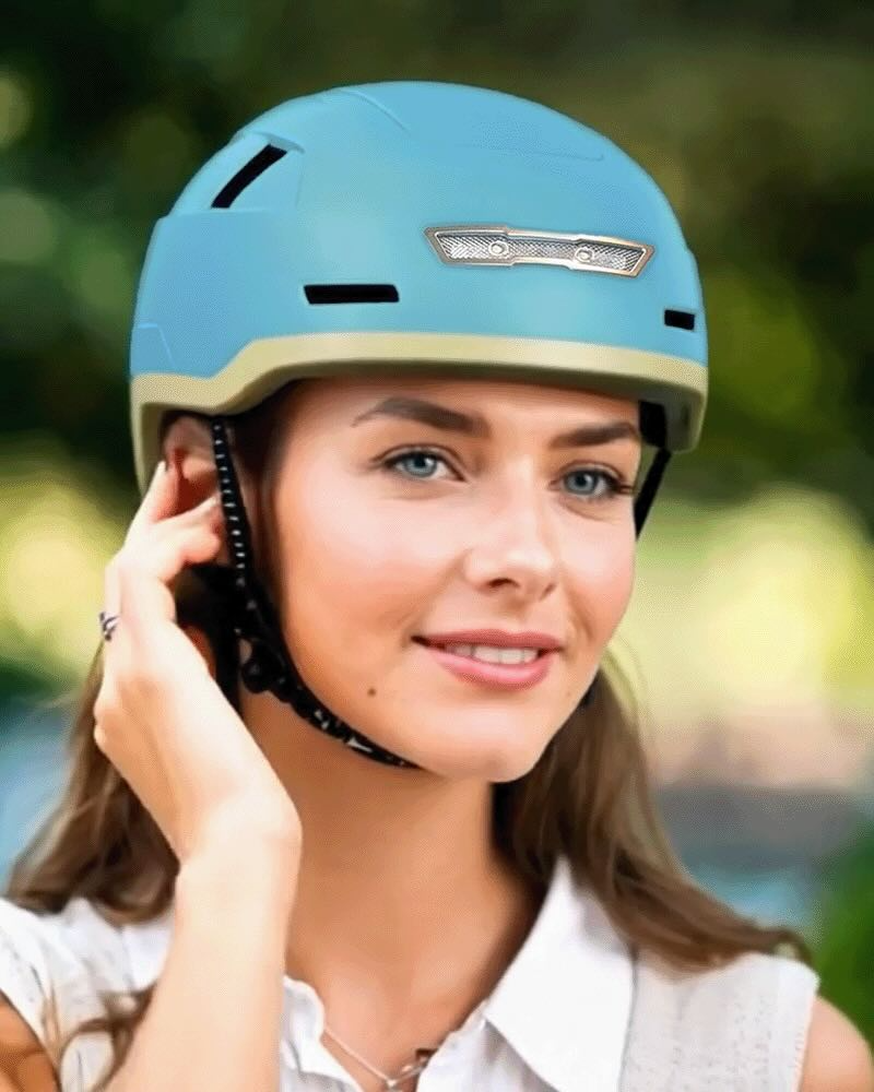 Outdoor, a person wearing the XNITO Helmet XNITO - Old School - Sky with integrated LED lights smiles while adjusting the chin strap.