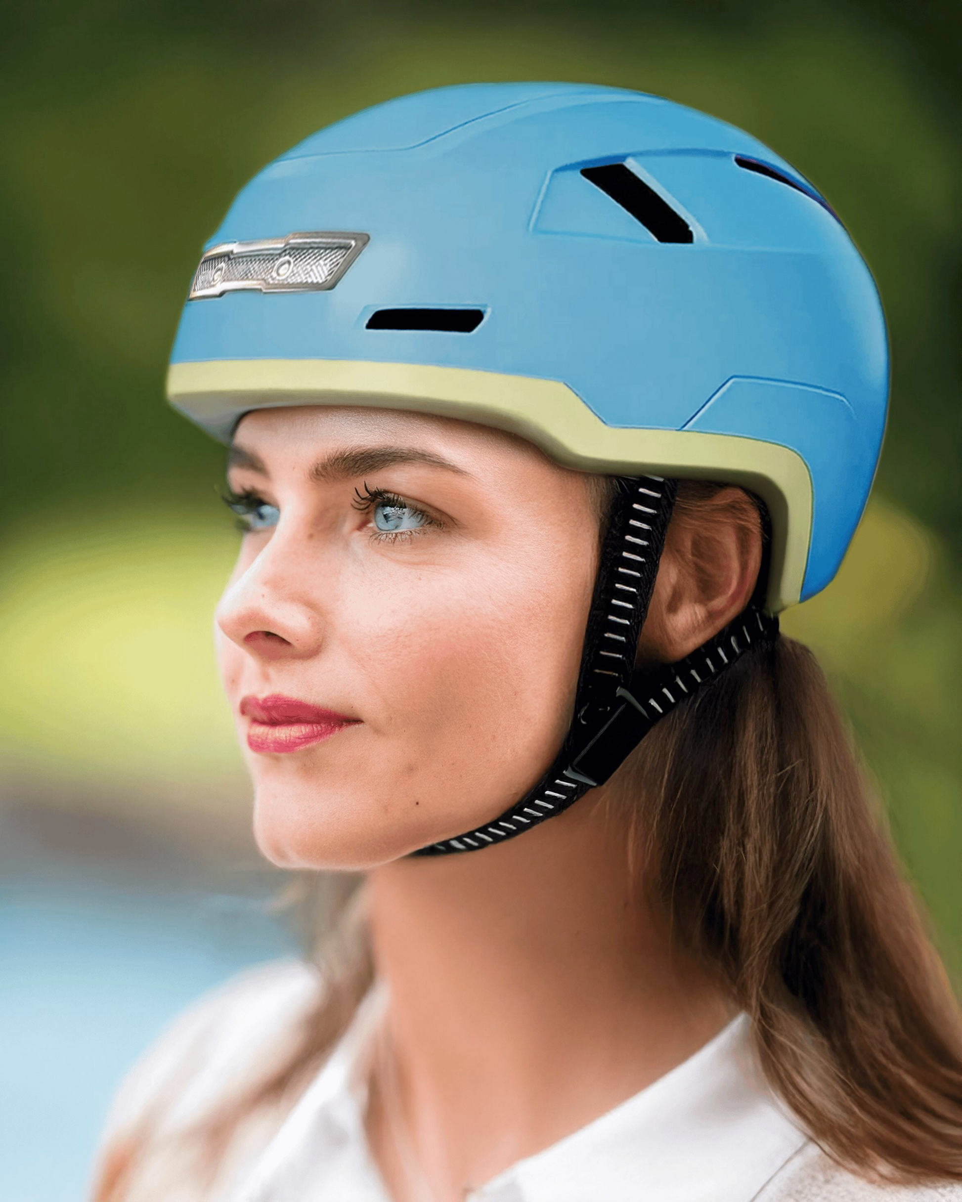 Against a blurred outdoor background, a person wears the XNITO Helmet XNITO - Old School - Sky with black straps and LED lights, enhancing visibility.