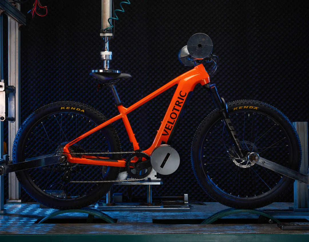 Orange Velotric Summit 1 electric bike displayed against a dark background with visible components and Velotric branding.