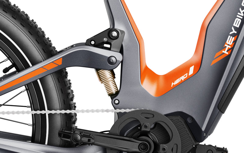 Close-up of a HeyBike - Hero (Mid-Drive) electric bike's rear frame, chain, and pedal mechanism, featuring an orange and grey color scheme.