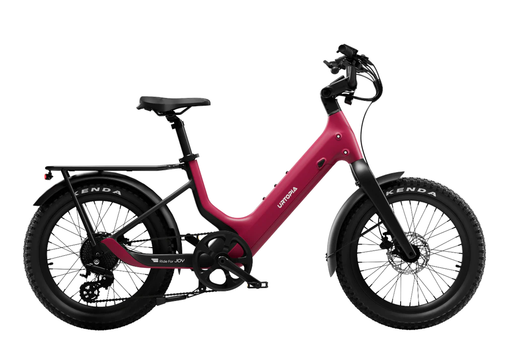 The Urtopia Carbon Joy Ultra by Urtopia is a red electric cruiser bike with a step-through frame, long-range battery, black saddle, rear rack, and fat tires, shown in side profile against a white background.
