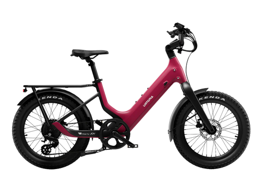 The Urtopia Carbon Joy Ultra by Urtopia is a red electric cruiser bike with a step-through frame, long-range battery, black saddle, rear rack, and fat tires, shown in side profile against a white background.