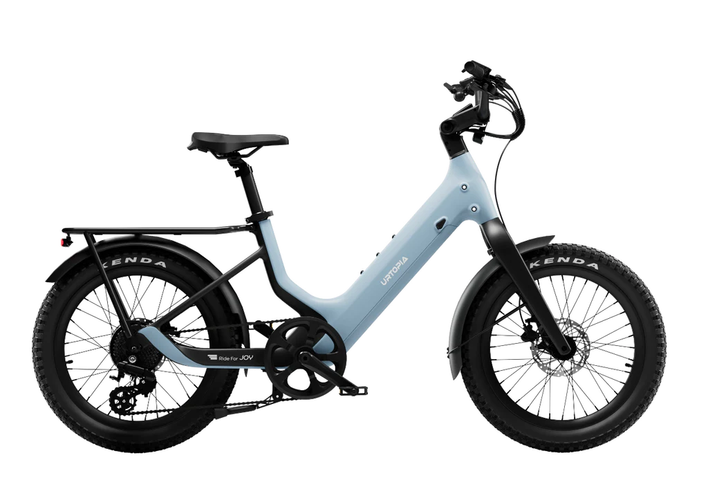 Side view of the Urtopia Carbon Joy Ultra, a light blue electric cruiser with thick tires, long-range battery, front suspension, rear rack, and step-through frame.