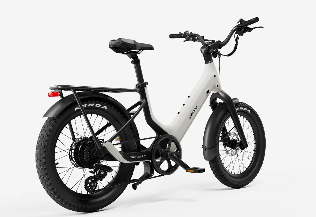 The Urtopia Carbon Joy Ultra by Urtopia is a white long-range electric bike with fat tires, rear rack, front and rear fenders, and a step-through frame shown from a rear side angle.