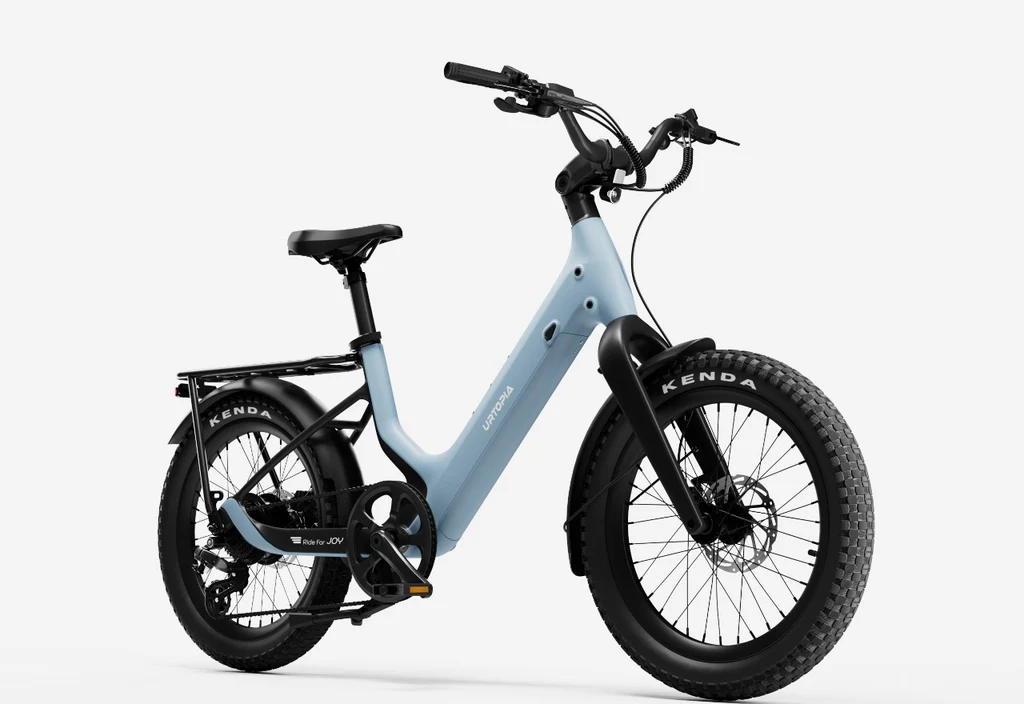 The Urtopia Carbon Joy Ultra by Urtopia, a light blue long-range electric bike with fat tires, rear cargo rack, and black handlebars, is displayed against a plain white background.